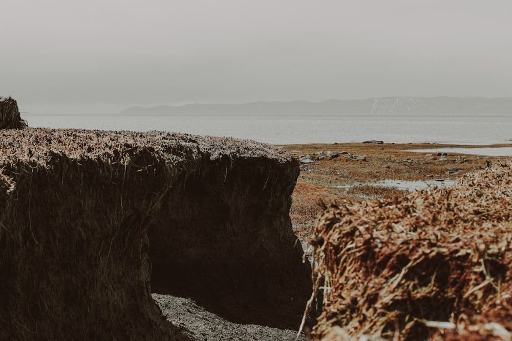 a man standing on top of a cliff next to a body of water