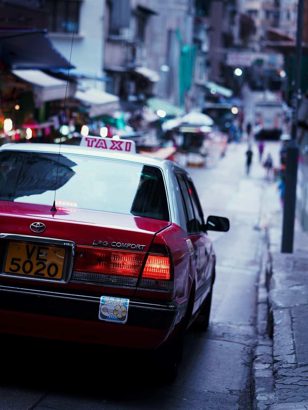 a red taxi cab parked on the side of a street