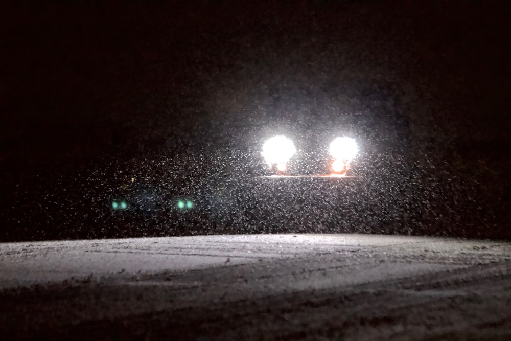 a car driving down a snow covered road at night