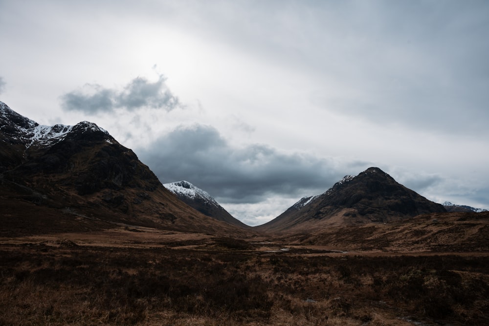 the mountains are covered in snow and brown grass