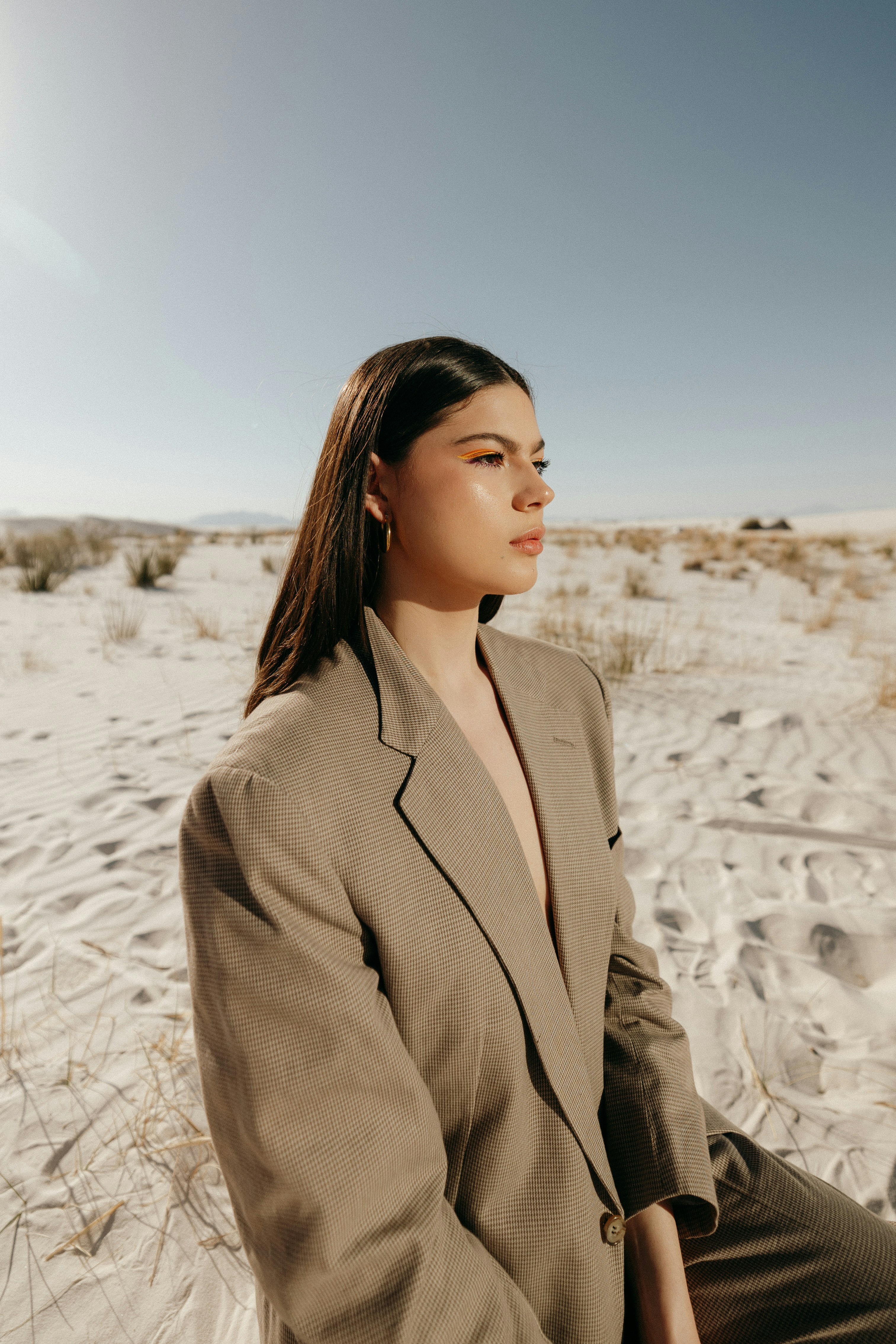 a woman in a suit sitting in the sand