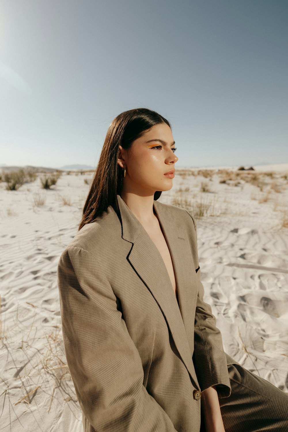 a woman in a suit sitting in the sand