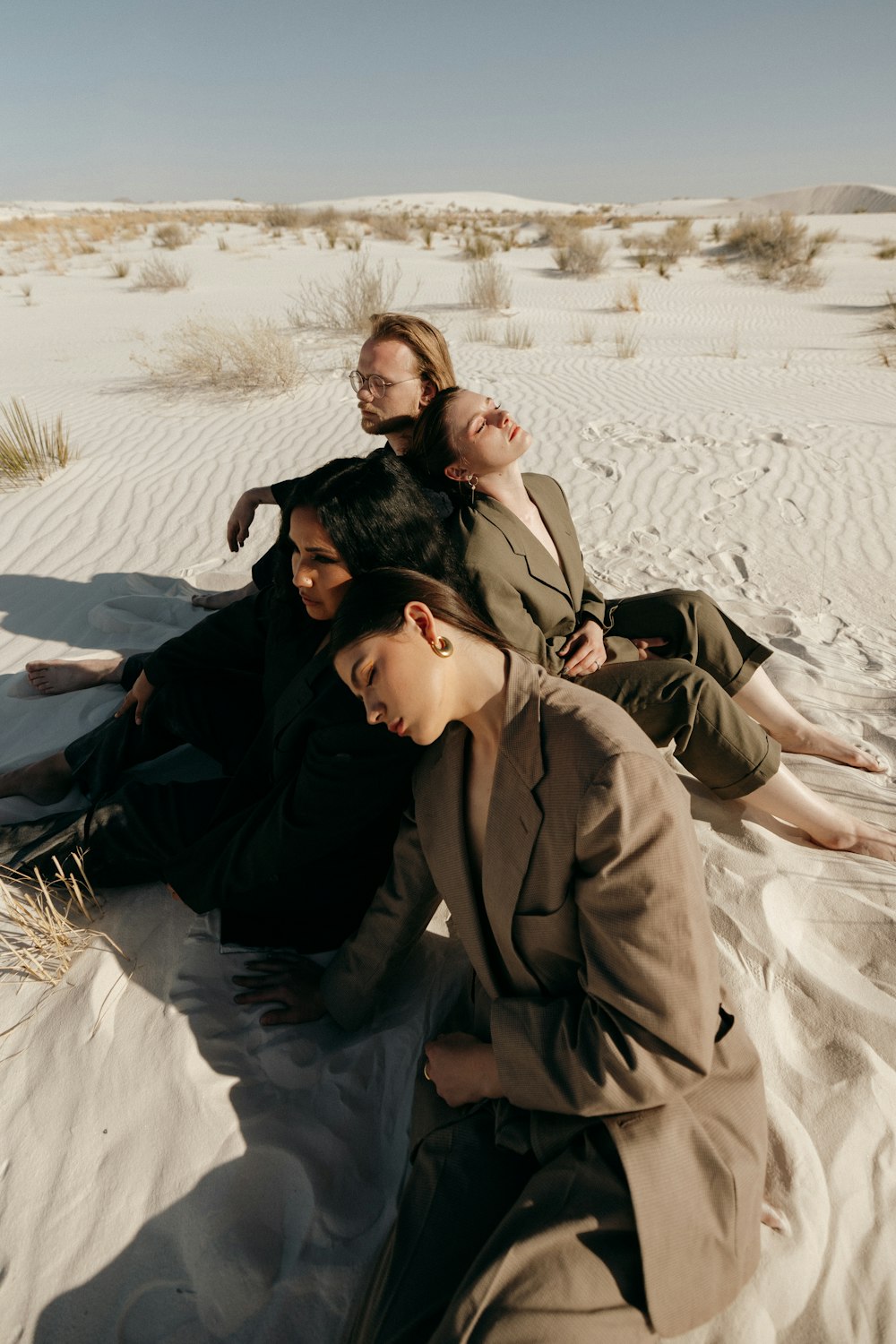 a group of people sitting on top of a sandy beach