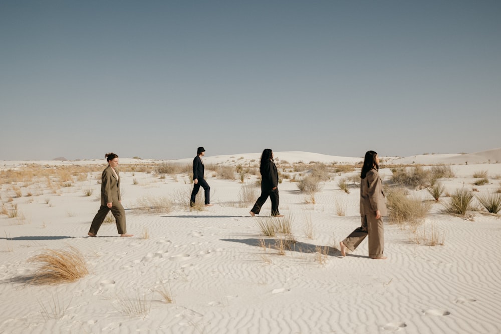 a group of people walking across a sandy field