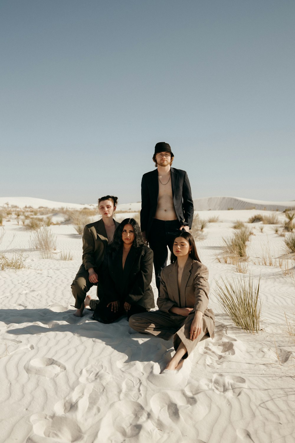 a group of people sitting on top of a sandy beach