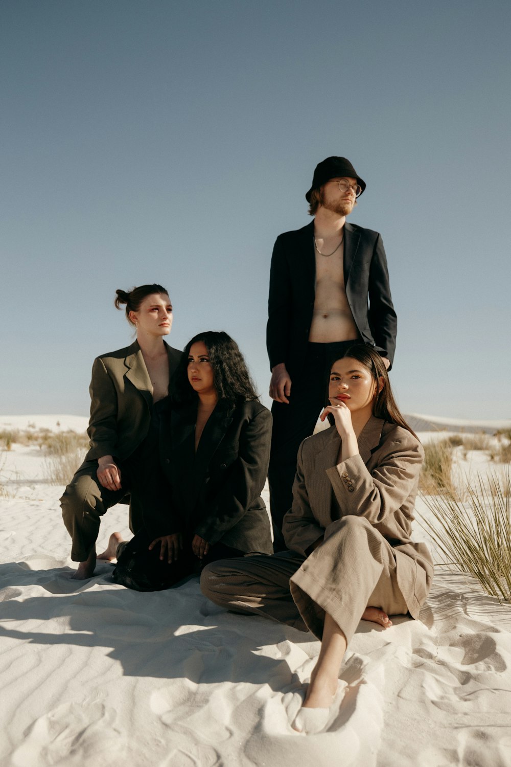 a group of people sitting on top of a sandy beach