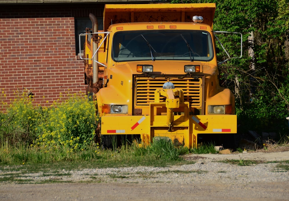 a yellow dump truck parked in front of a brick building