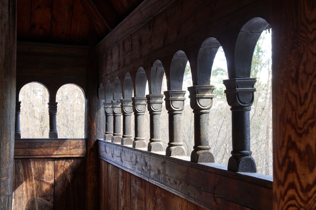 a wooden wall with a row of arched windows, Norwegian wooden stave church exterior hallway with carved columns