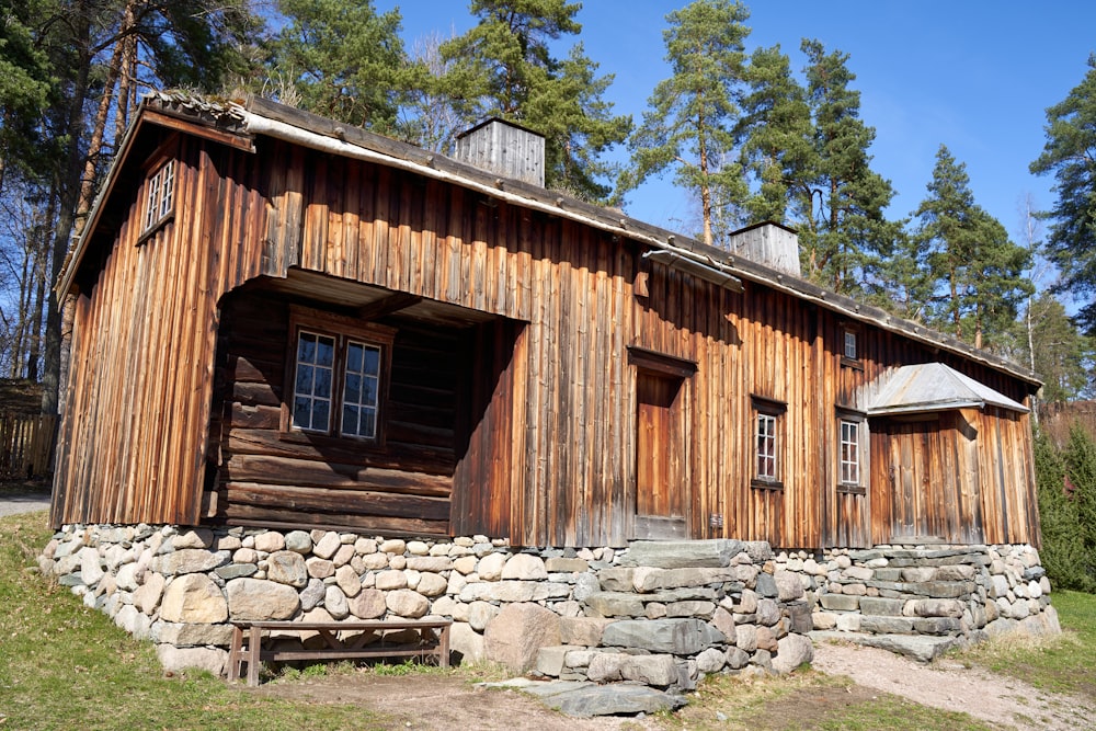 a wooden building with a stone wall and a bench in front of it