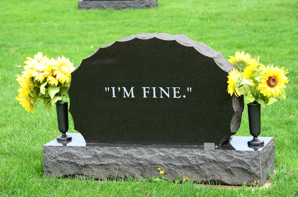 a headstone with sunflowers on it in the grass