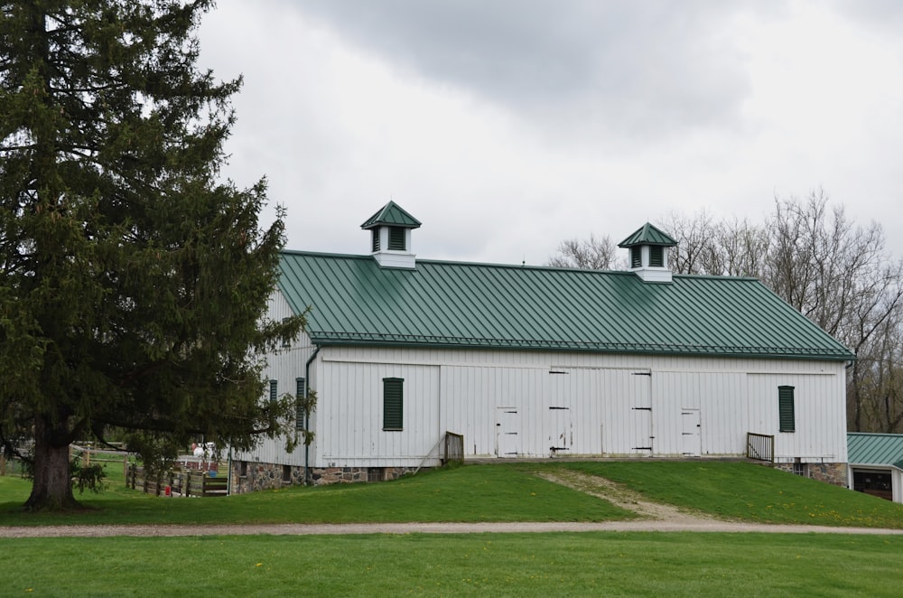a large white barn with a green roof
