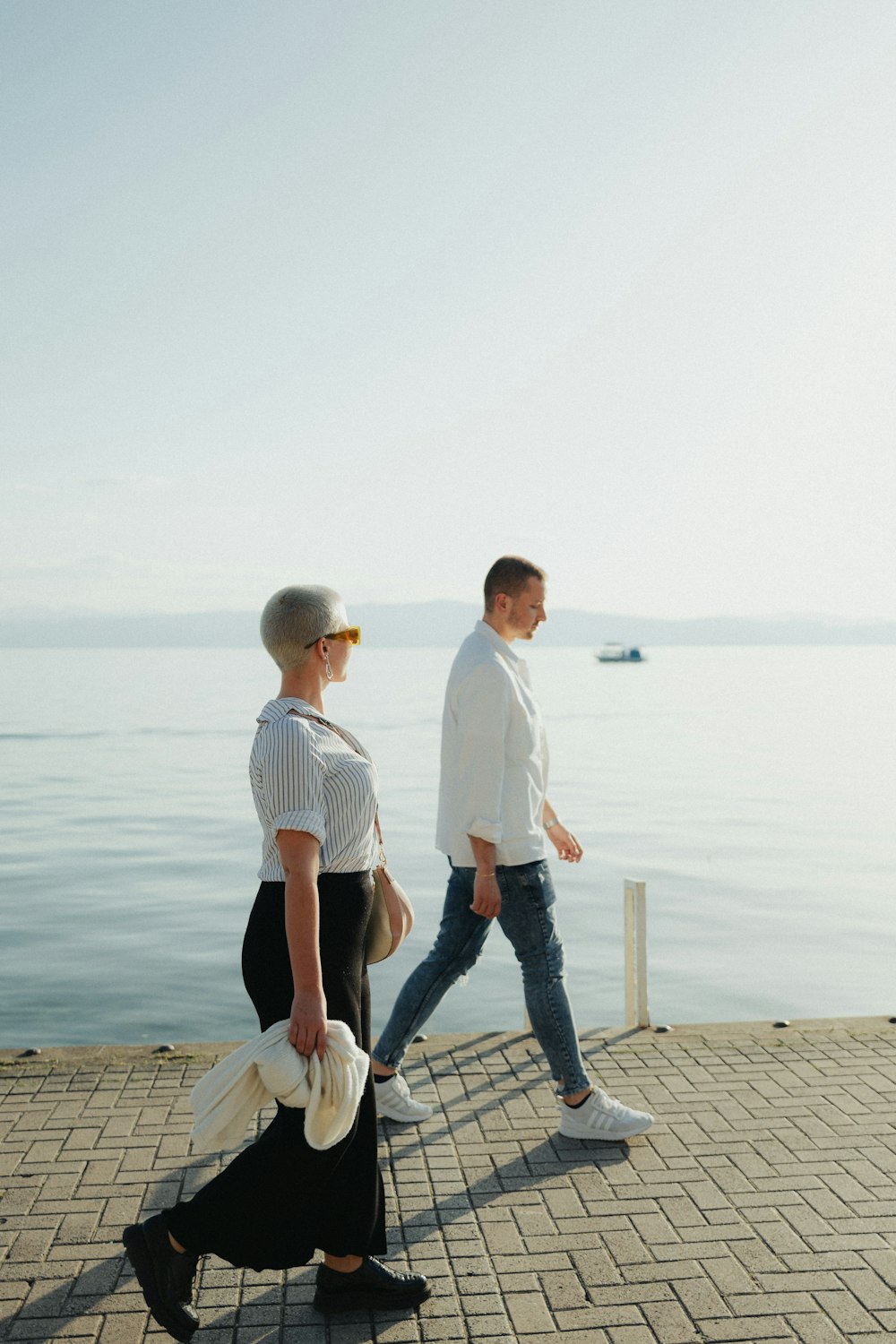 a man and a woman walking along the water