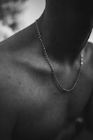 black and white photograph of a man wearing a chain necklace