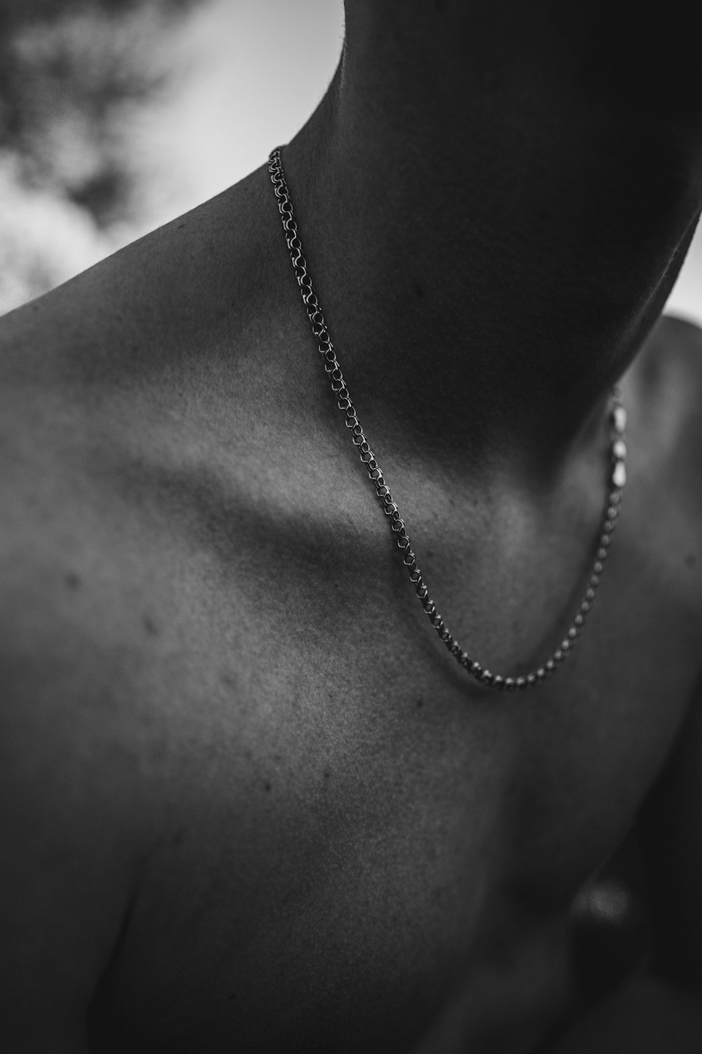 Photographie en noir et blanc d’un homme portant un collier en chaîne