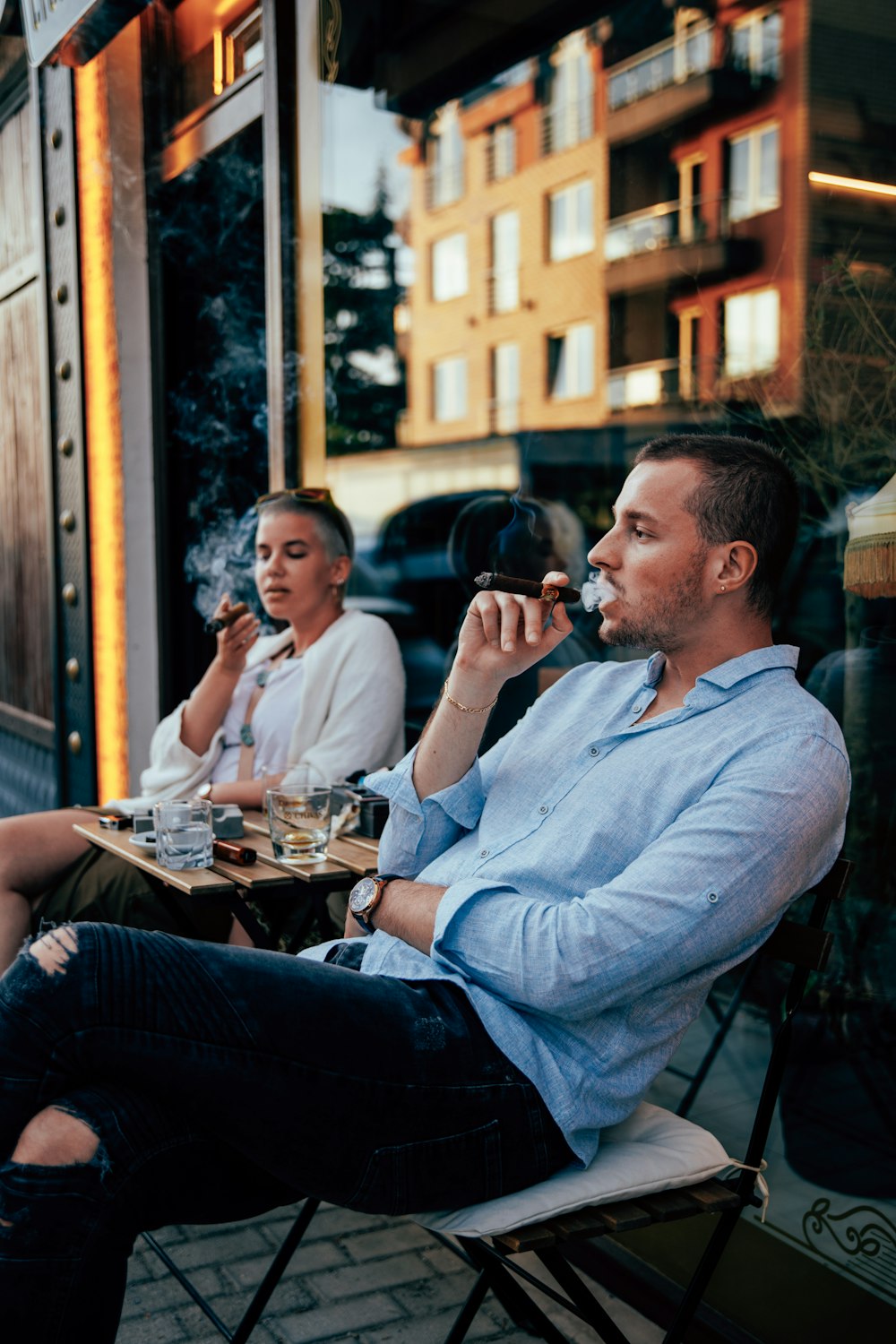 a man and a woman sitting at a table outside of a restaurant