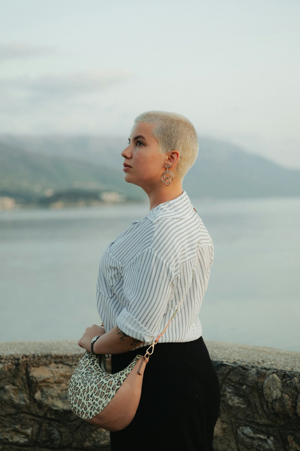 a woman with short hair is standing by the water