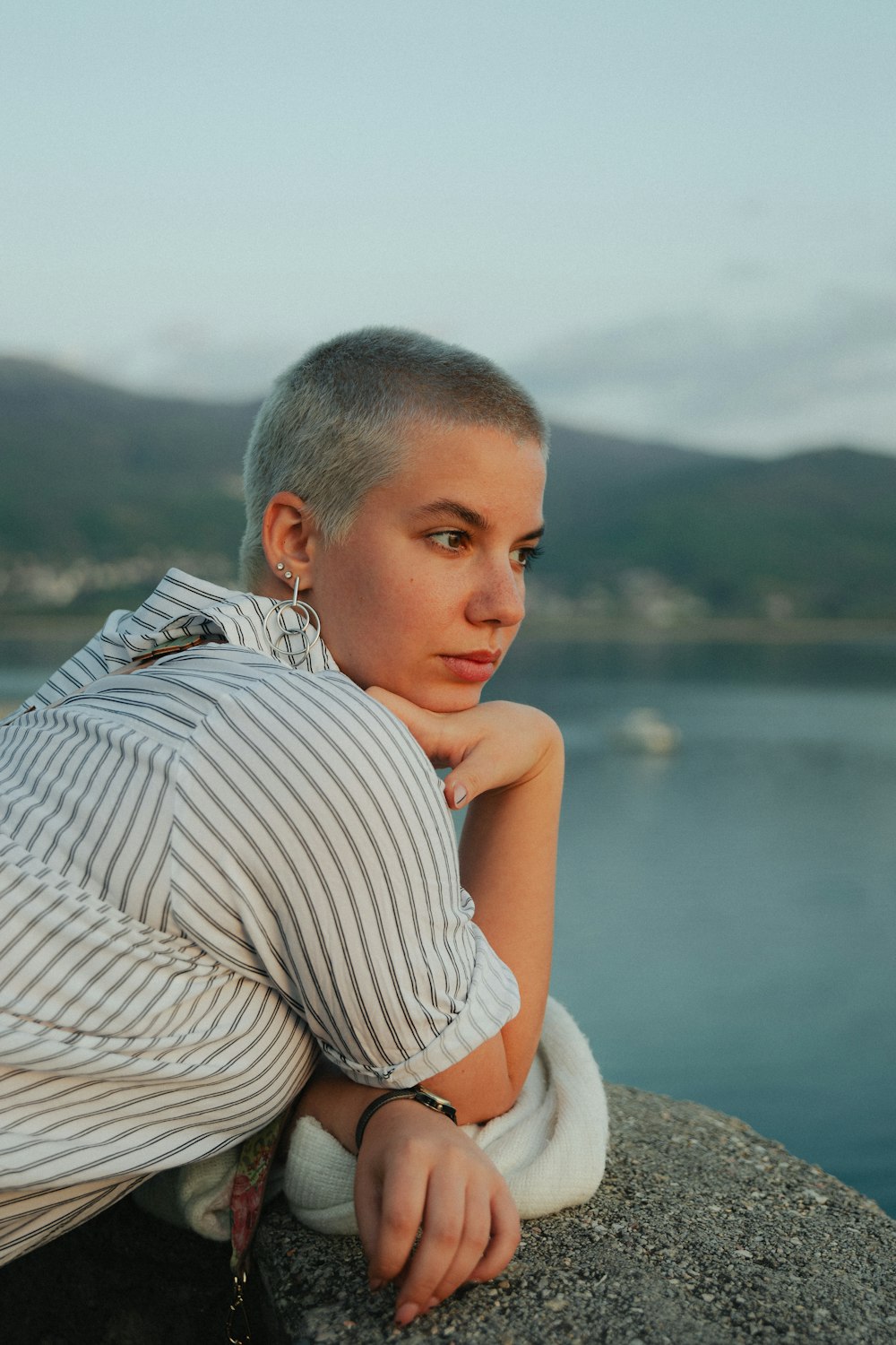 a woman sitting on top of a rock next to a body of water