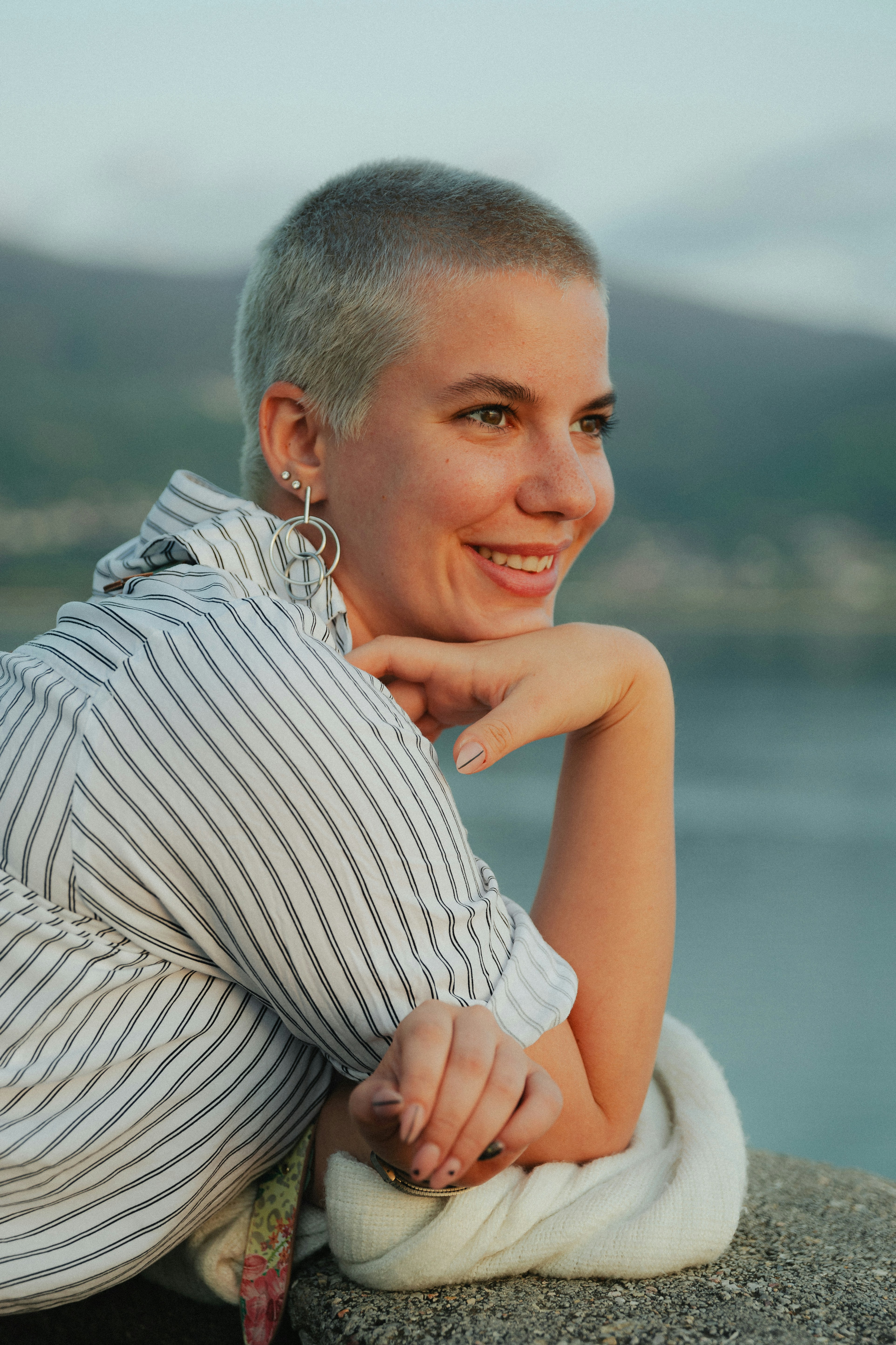 a woman sitting on top of a rock next to a body of water