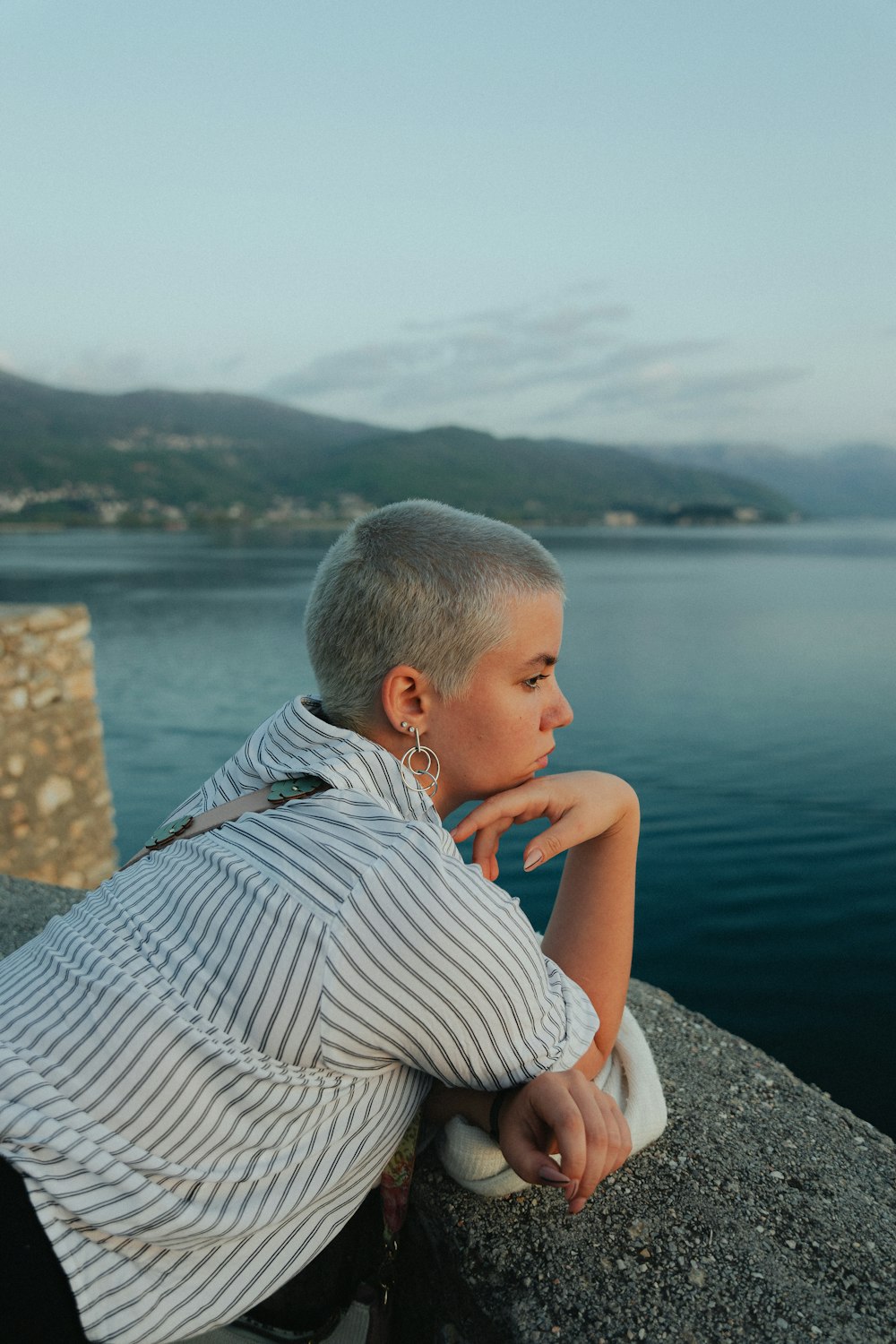 a woman sitting on a rock next to a body of water