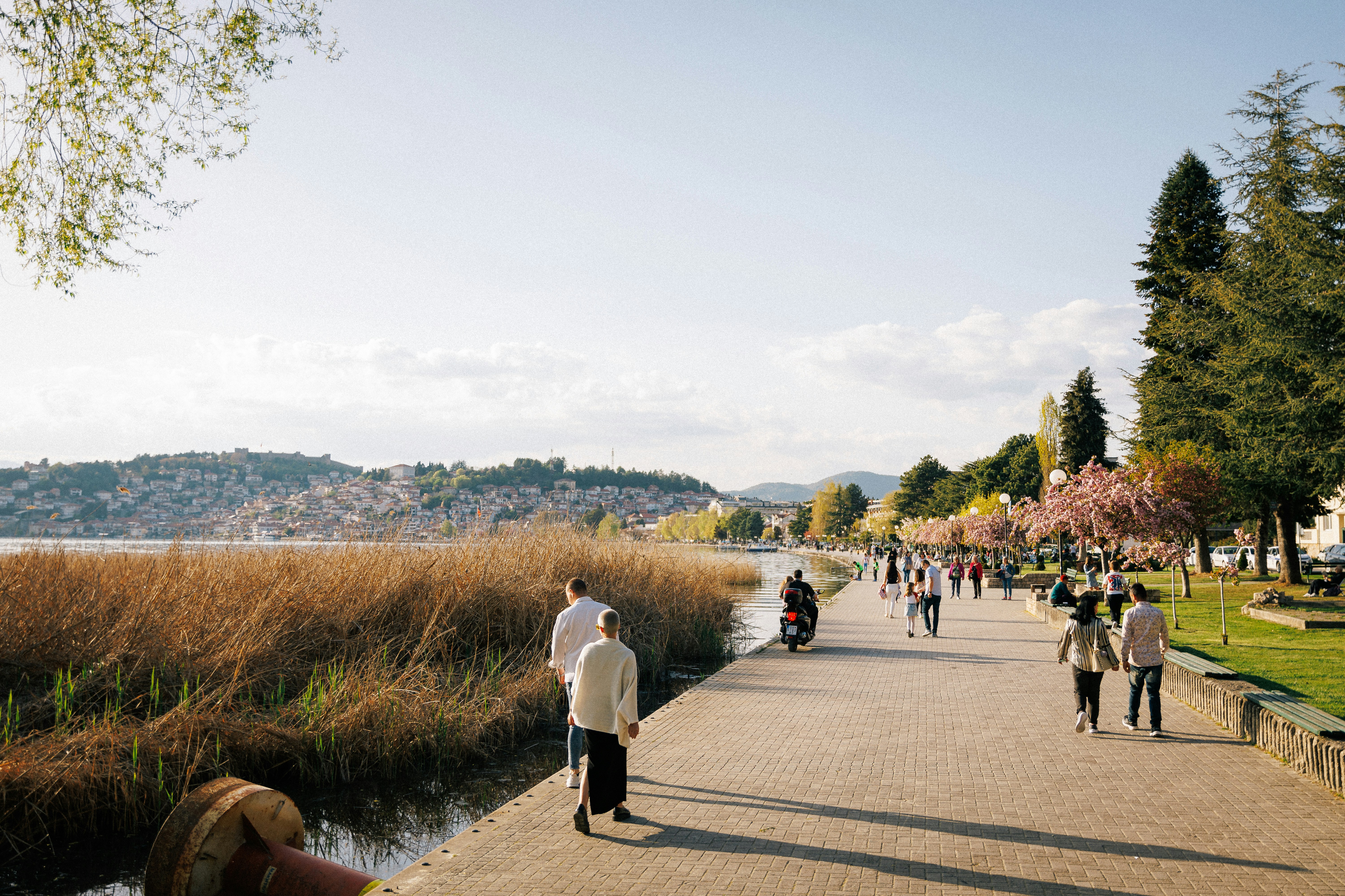 a group of people walking down a sidewalk next to a river