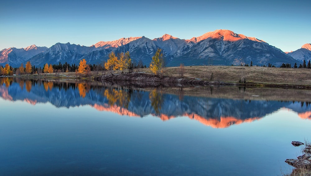 a mountain range is reflected in the still water of a lake