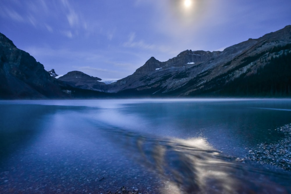a full moon shines over a mountain lake