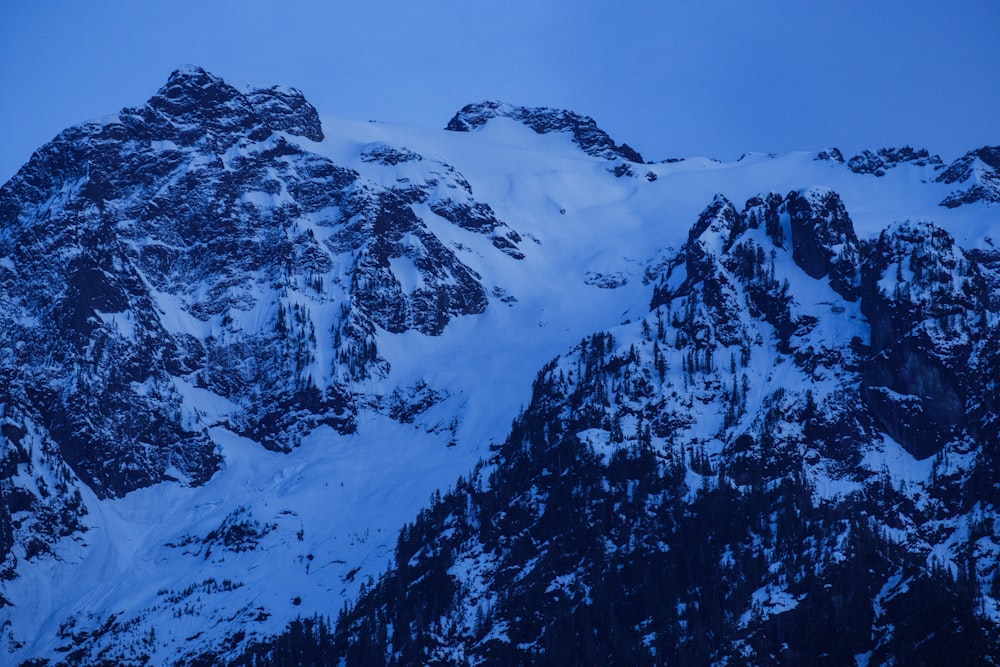 a large mountain covered in snow under a blue sky