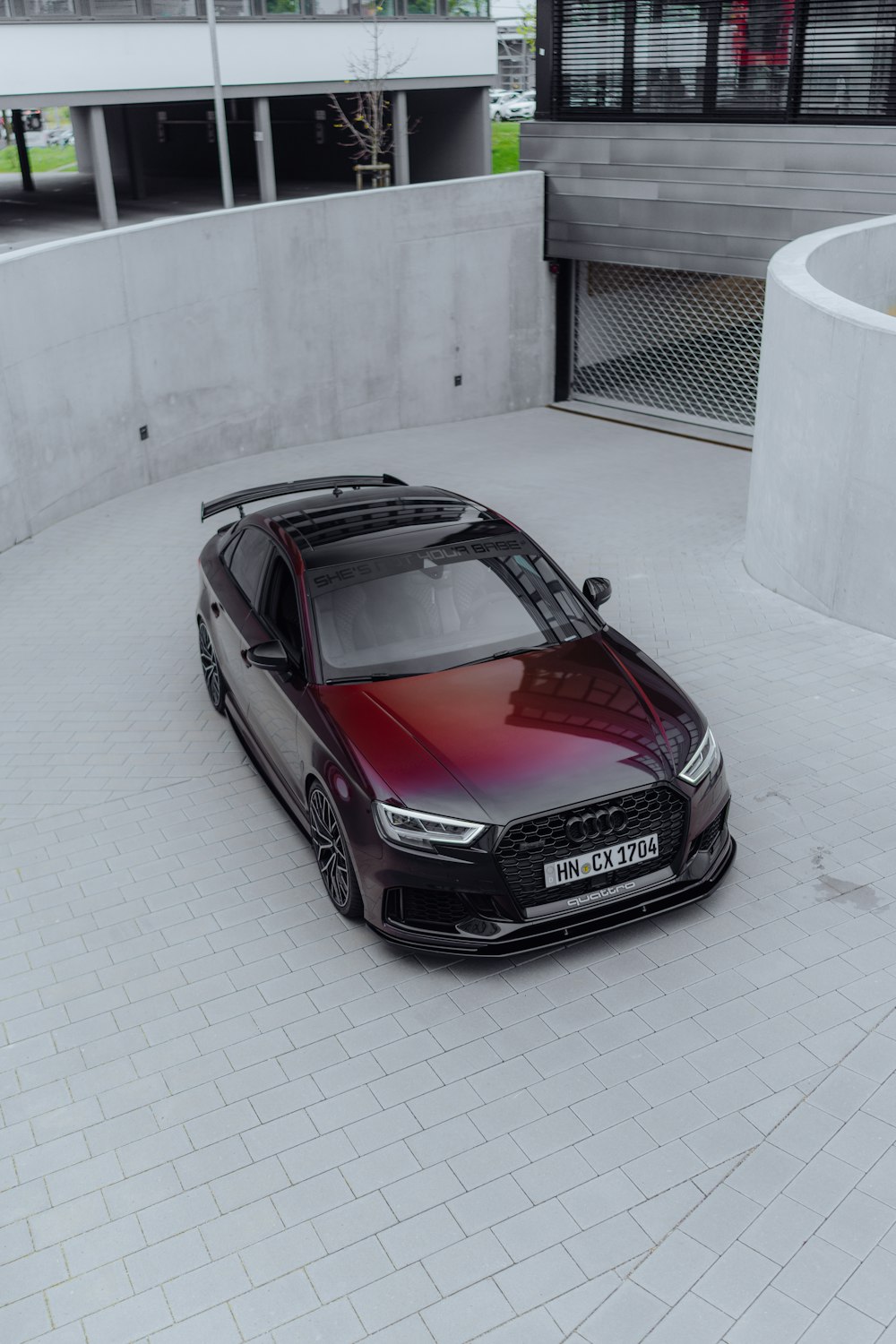 a red and black car parked in front of a building