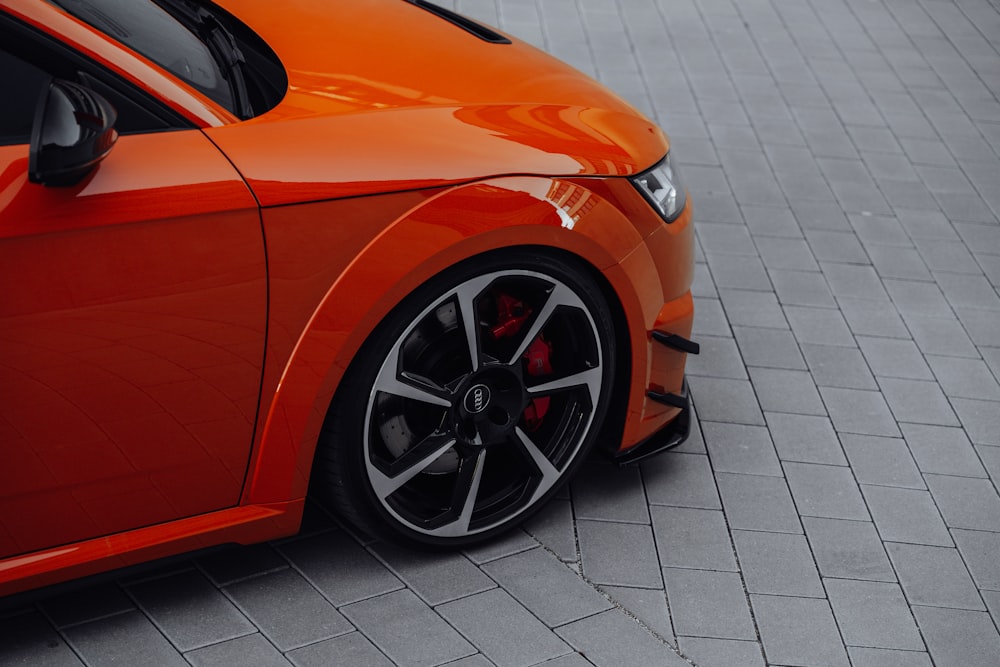 an orange sports car parked on a brick road