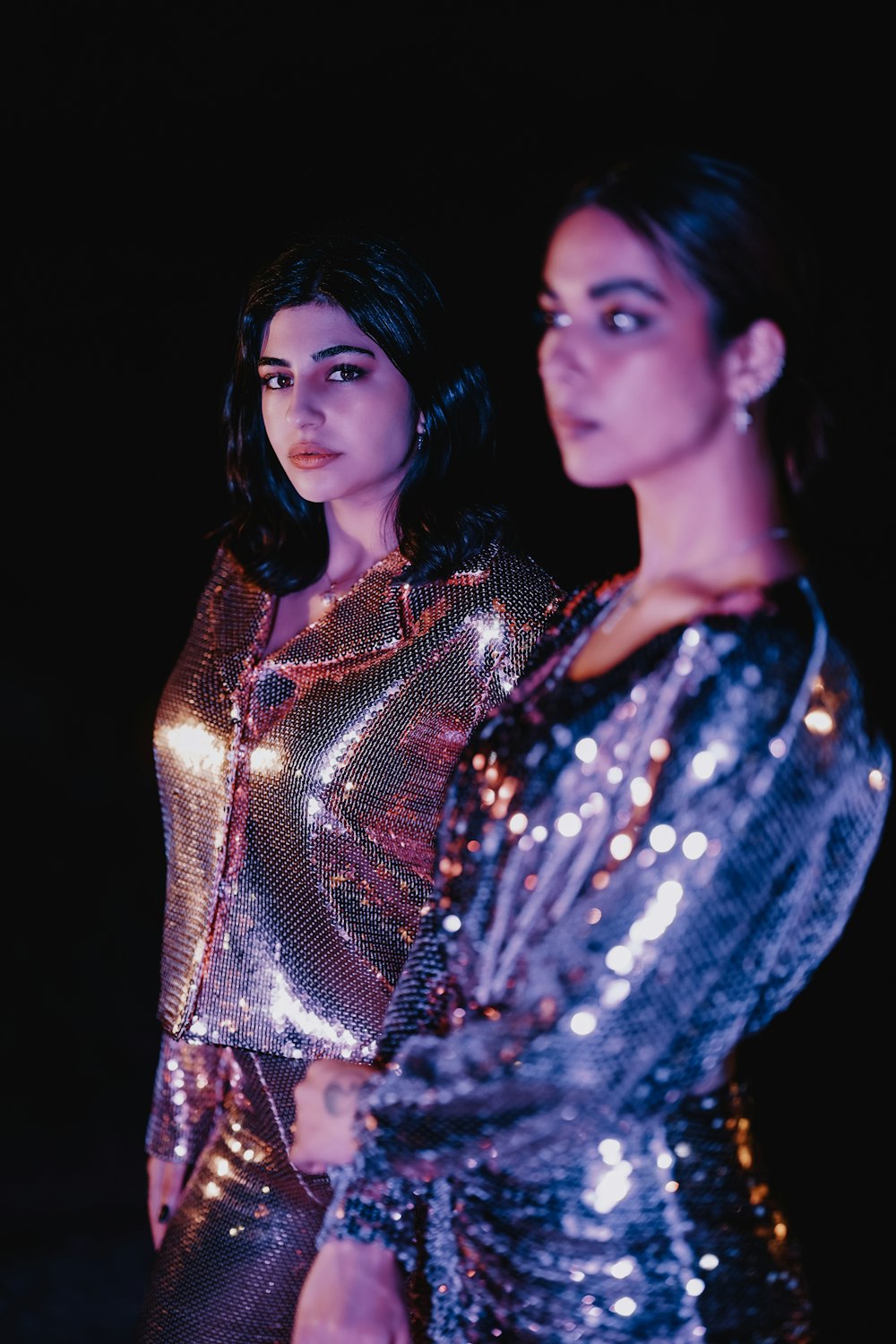 two women standing next to each other in shiny outfits
