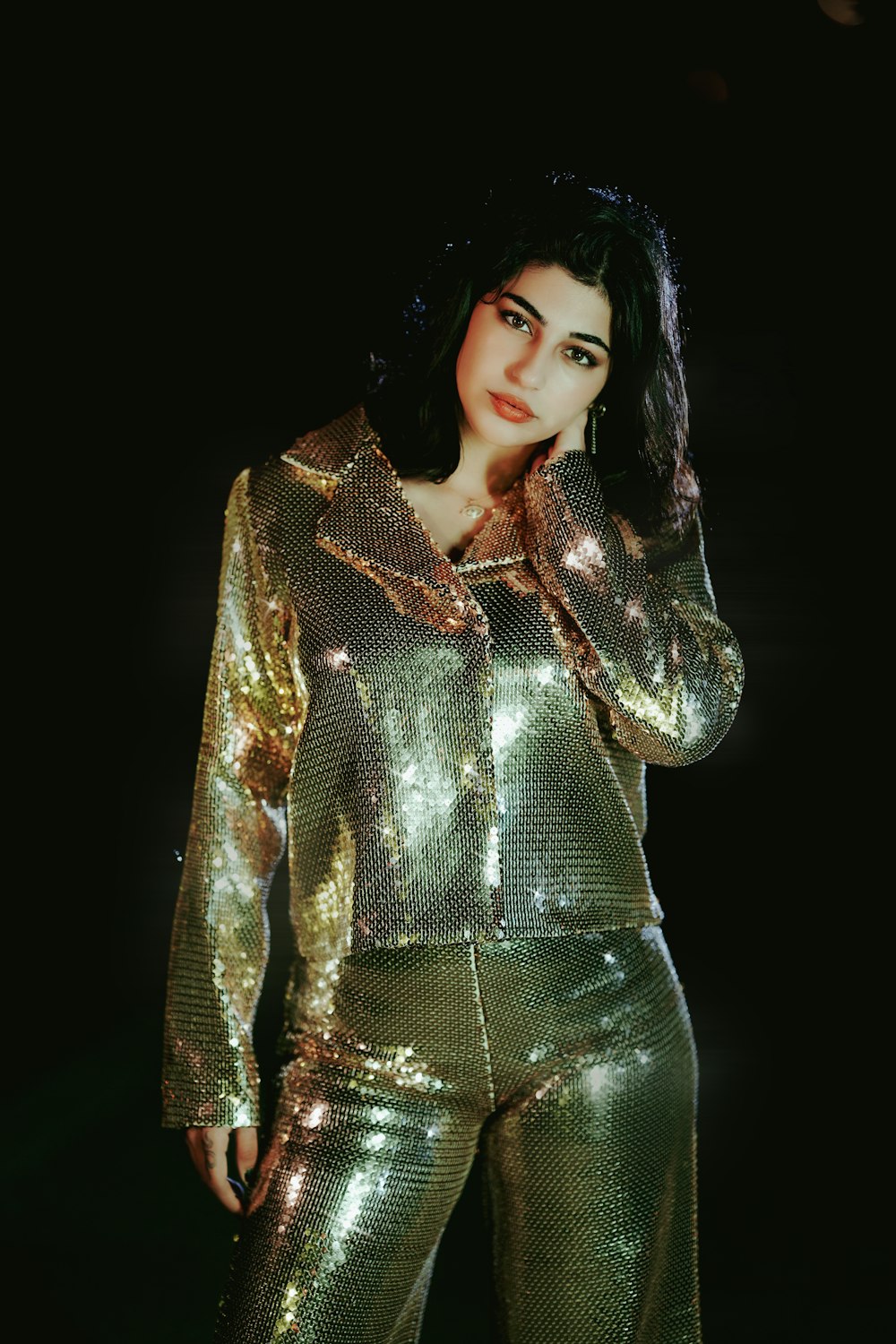 a woman in a gold sequin suit posing for a picture
