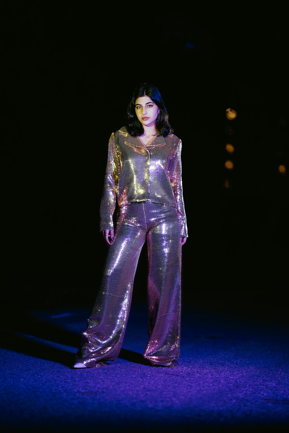 a woman in a shiny purple outfit standing in the dark