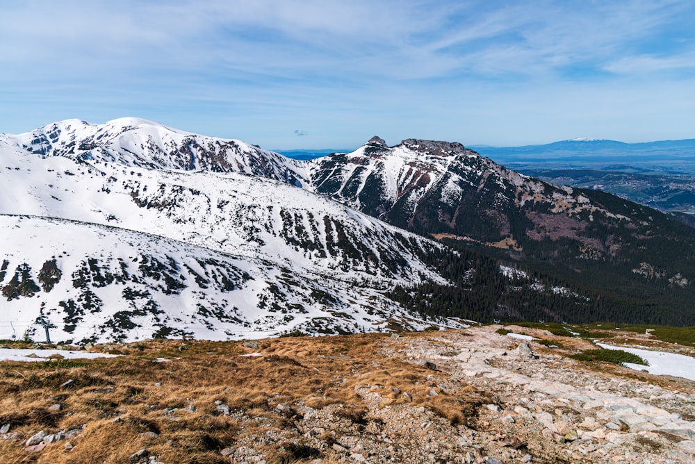 a view of a snowy mountain range from the top of a hill