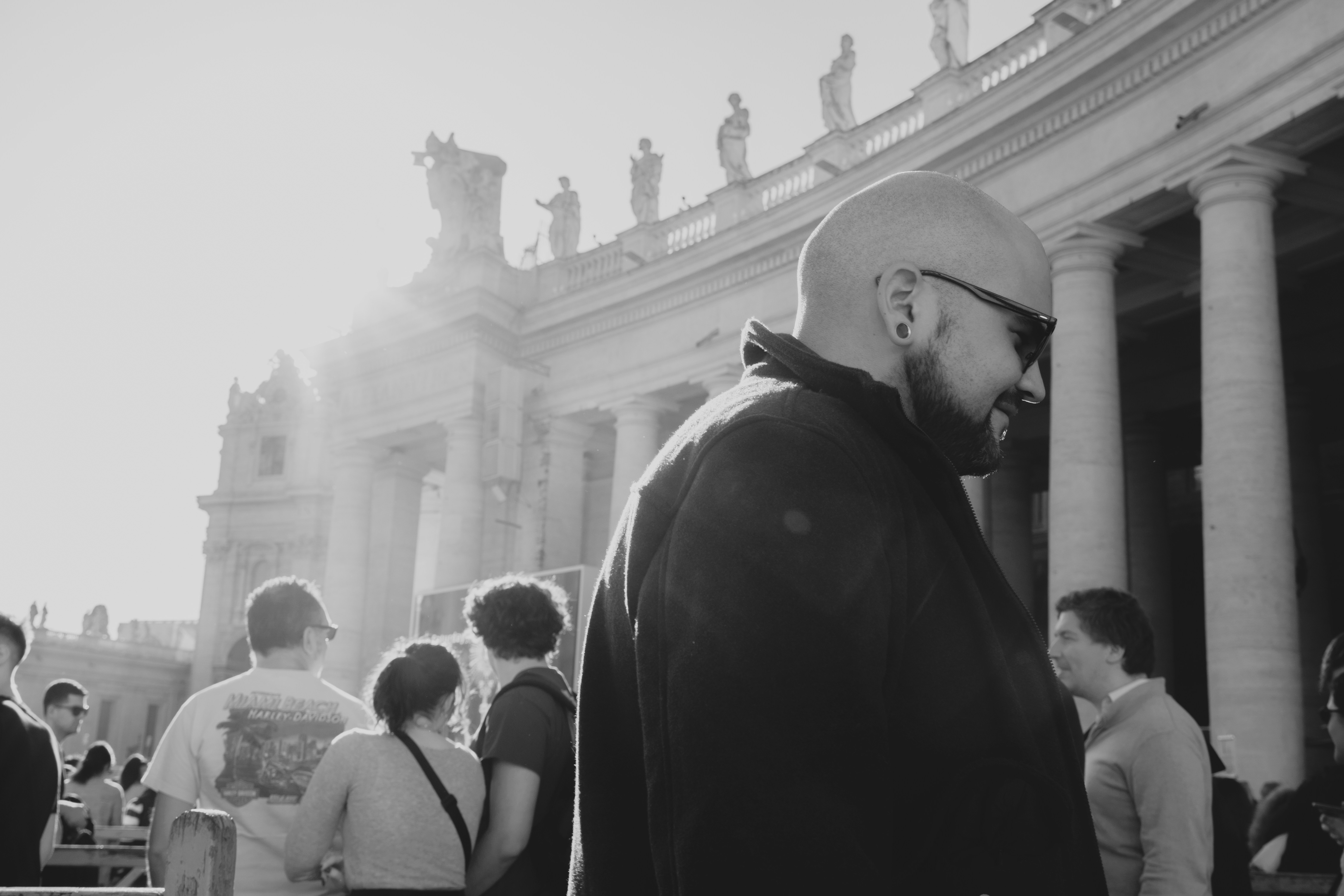 a man in a hat and sunglasses standing in front of a building