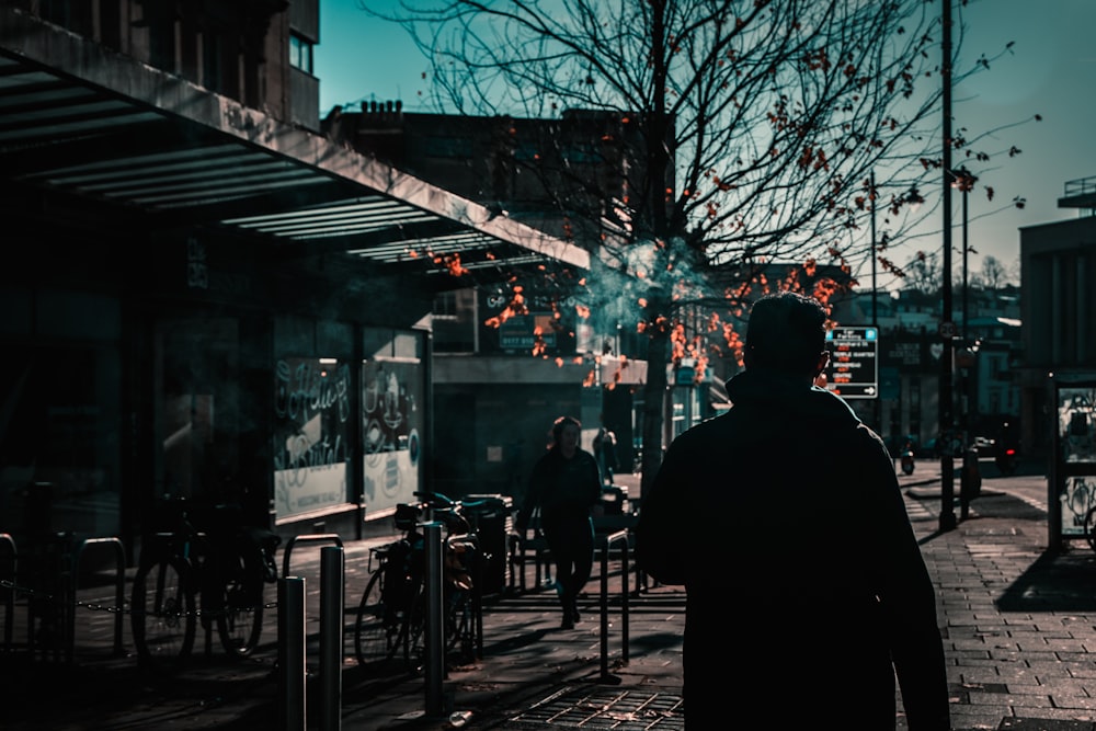 a man walking down a street next to tall buildings