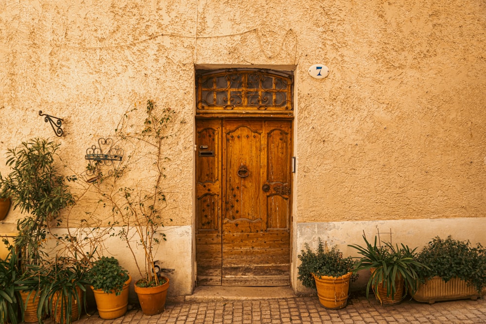 a yellow building with potted plants and a wooden door
