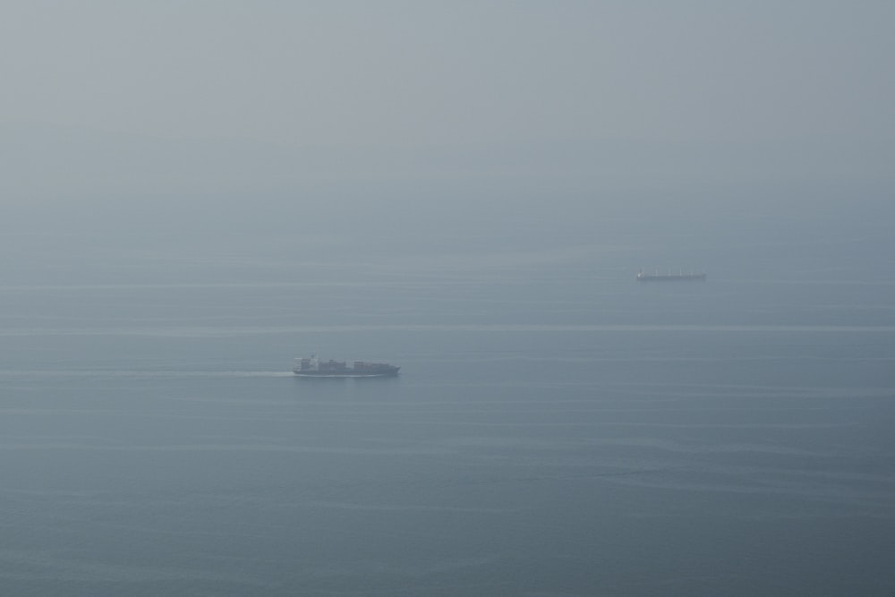 a boat in the middle of the ocean on a foggy day