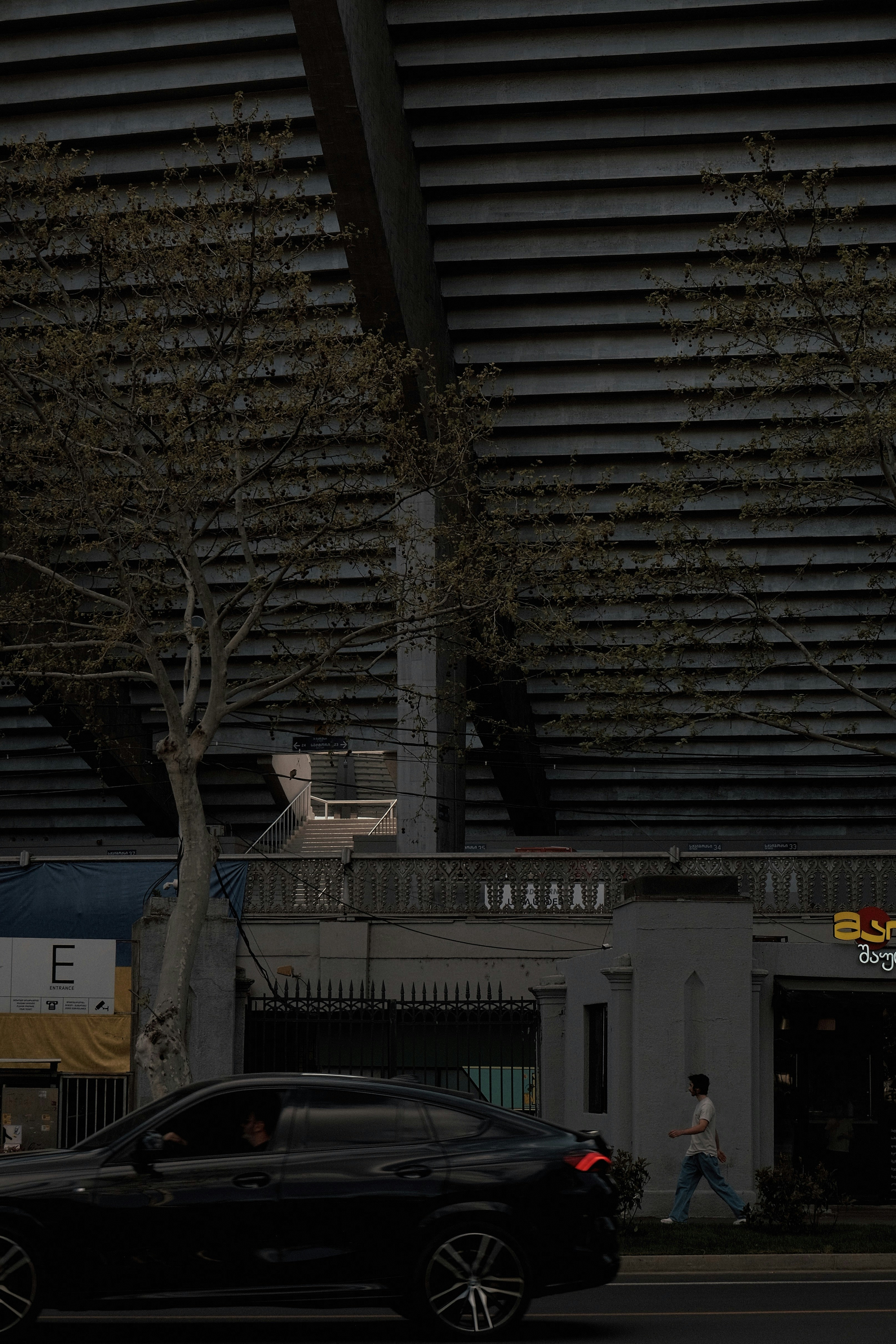 a black car driving down a street next to a tall building