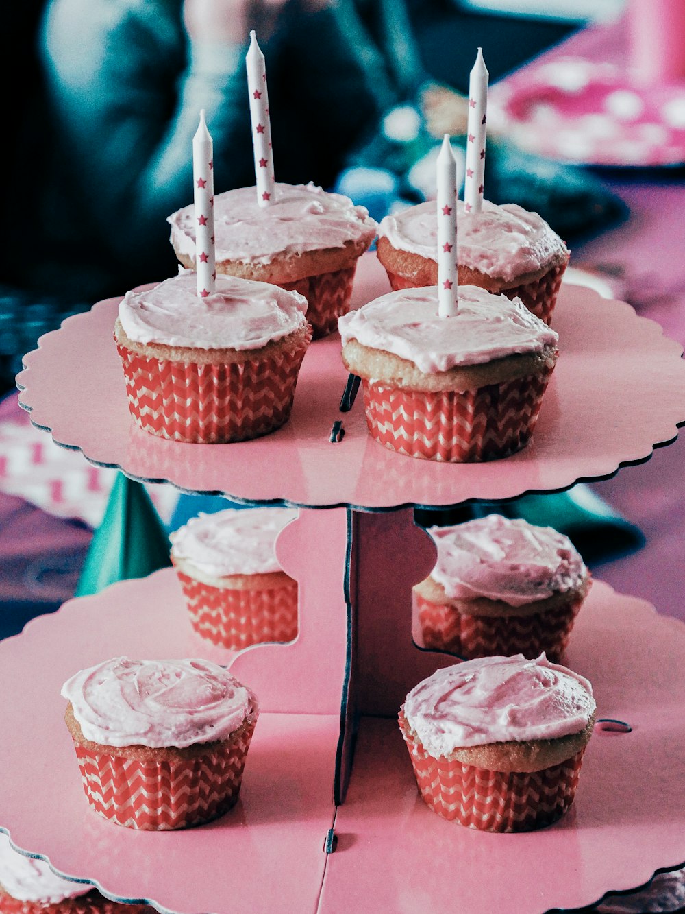 cupcakes with white frosting and lit candles on a pink tray