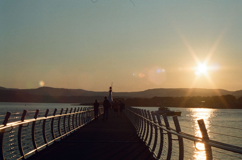 the sun is setting over the water on a pier