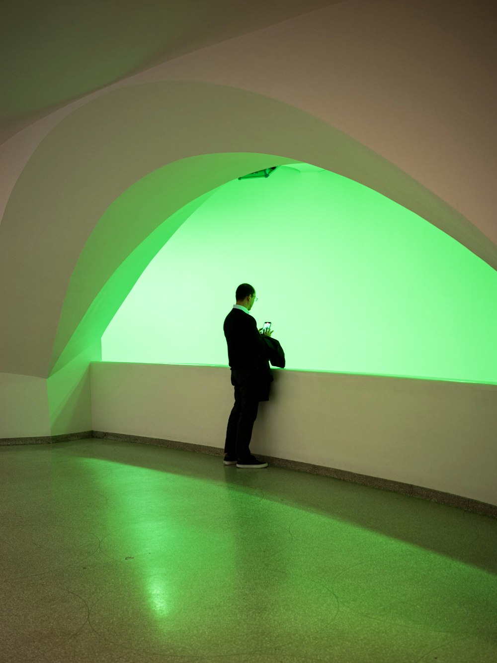 a man in a suit standing in a room with a green light
