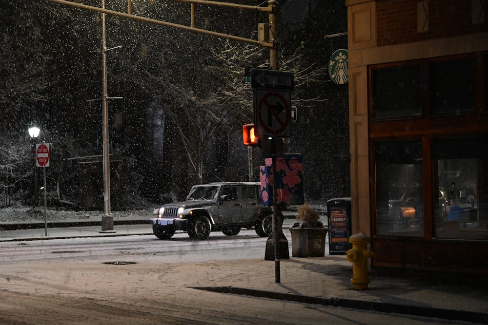 a truck driving down a snow covered street at night