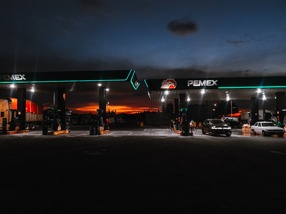 a gas station at night with cars parked in the lot