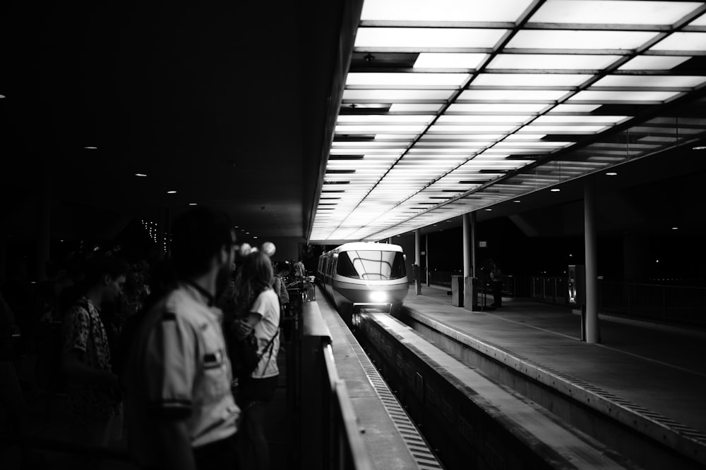 a black and white photo of a train pulling into a station