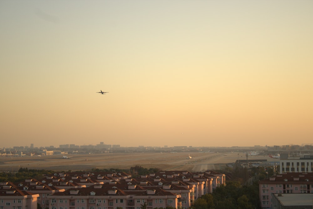 an airplane is flying over a city at sunset