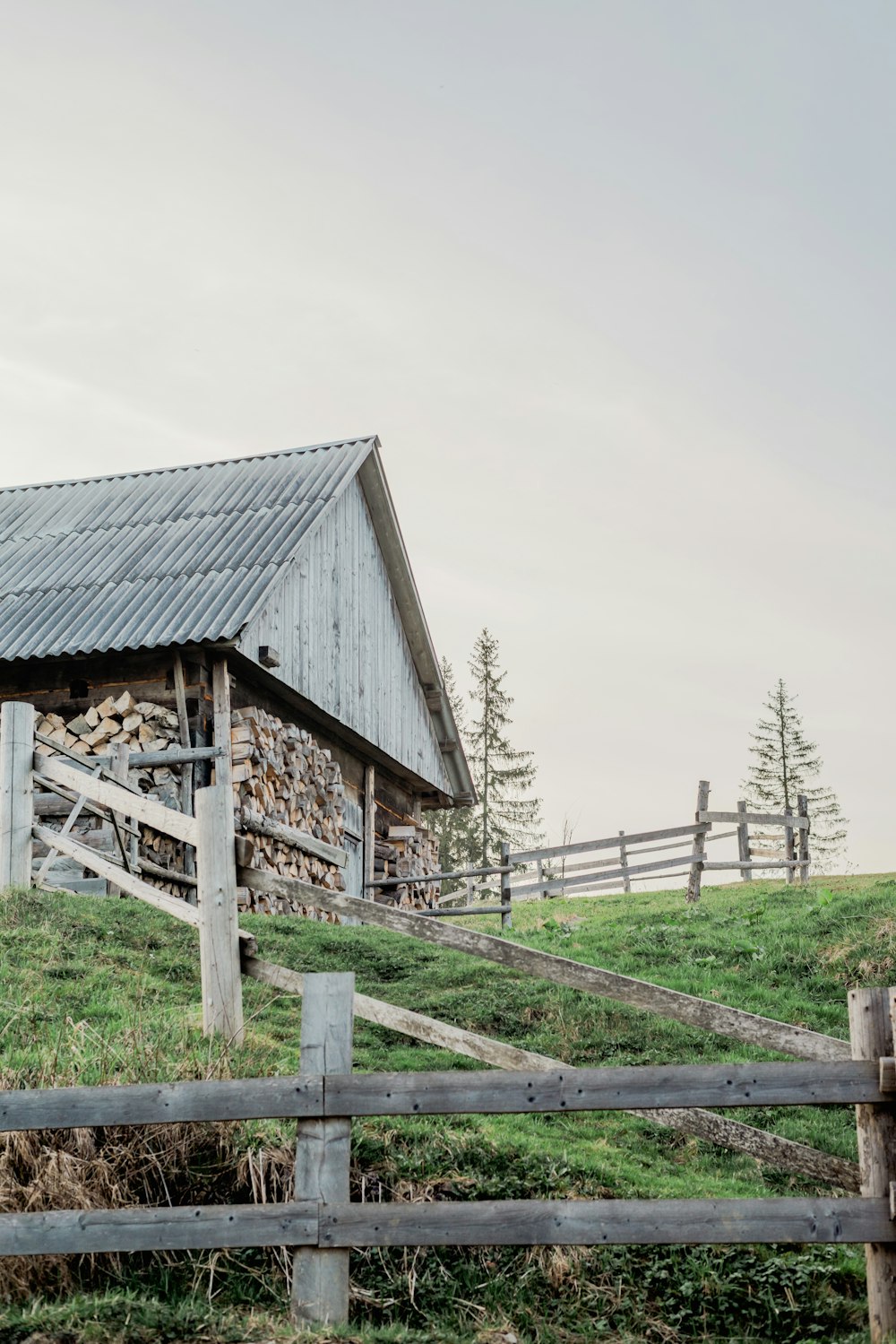 a wooden barn with a metal roof on a hill