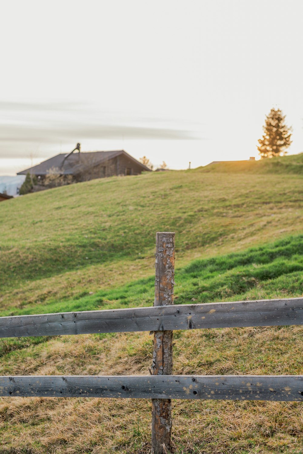 a wooden fence in front of a grassy hill