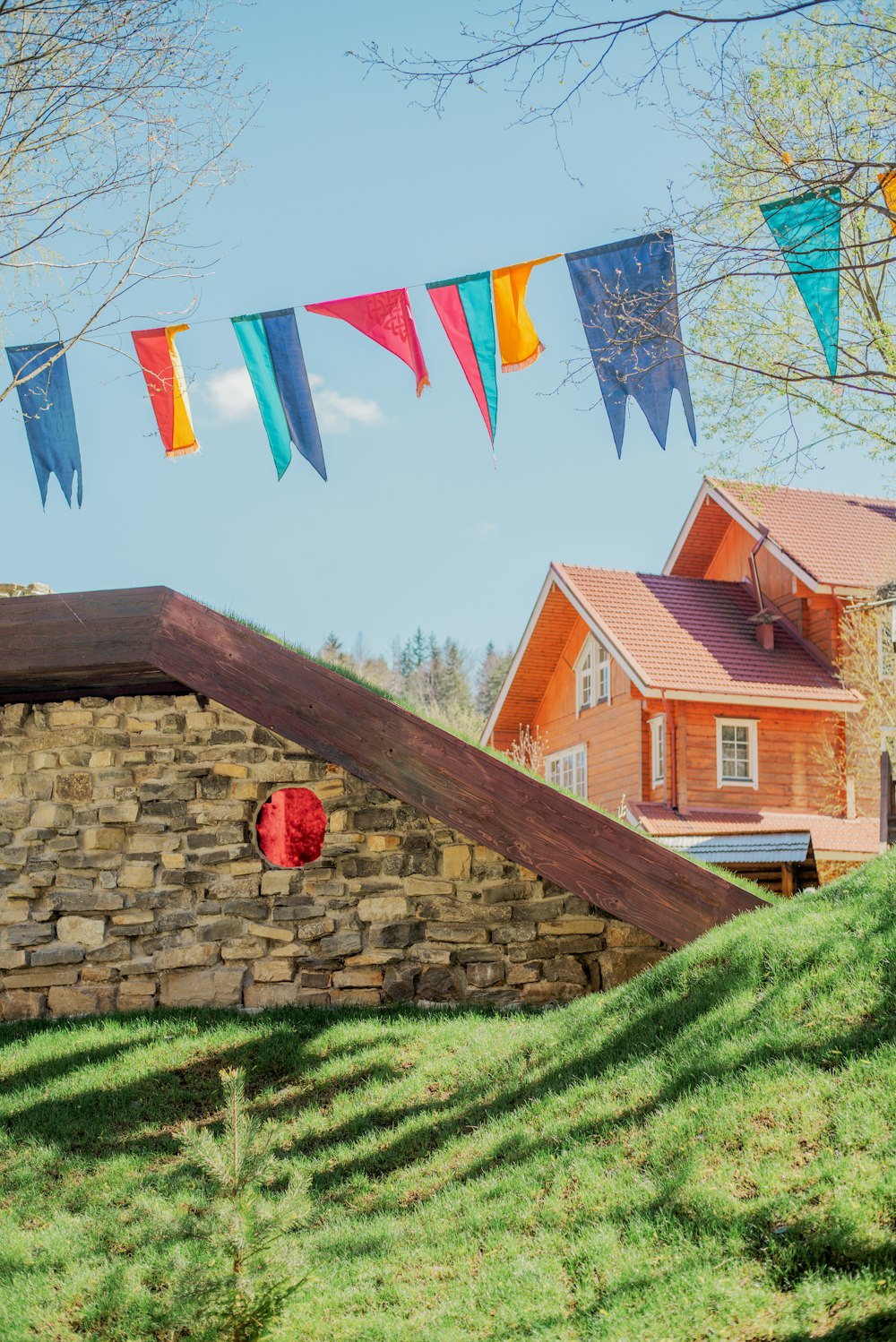 a stone wall with bunting and a house in the background