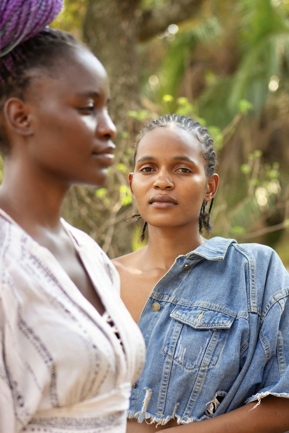 two women standing next to each other in a forest