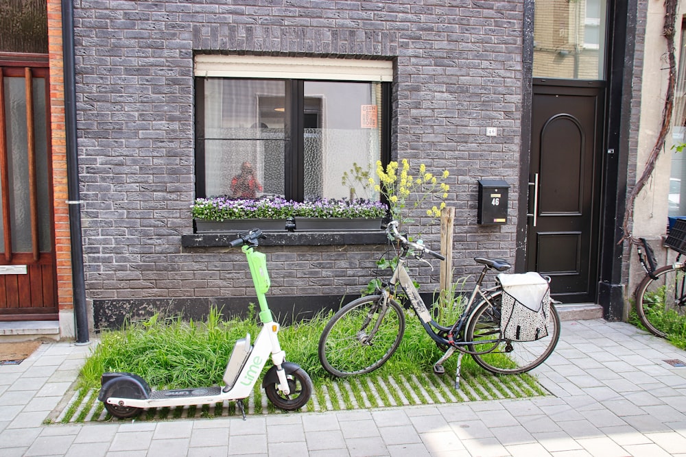 a scooter parked next to a bicycle on a sidewalk